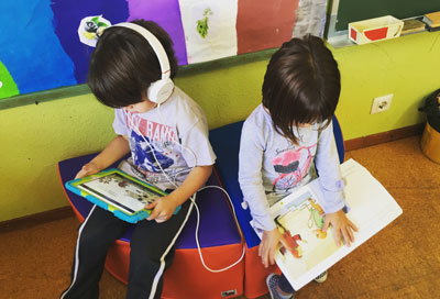 Alumno y alumna en el rincón de la biblioteca escuchando un audiocuento creado por ellos/as y sus compañeros