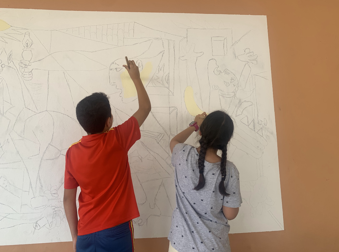 Fotografía en la que aparecen dos niños comenzando a pintar el Guernica