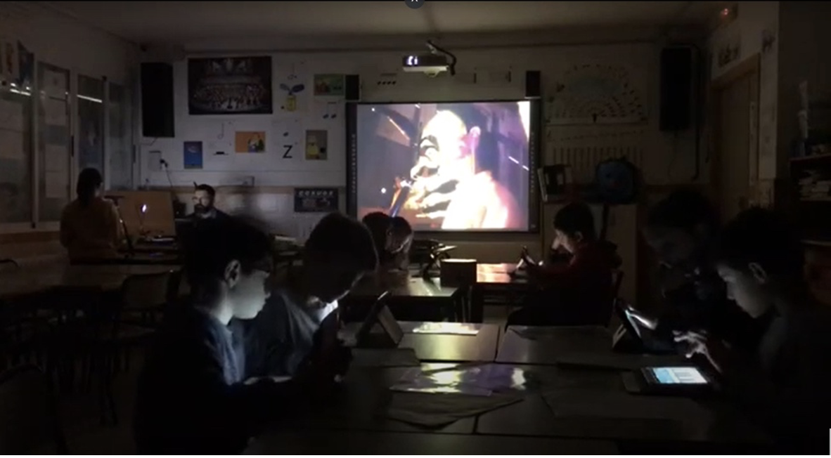 Fig. 1 Historia de miedo con Soundcool El Asesinato, con el profesor Carles Rodríguez en el CEIP Carmelo Ripoll. Los y las estudiantes controlan con sus móviles/tabletas el sonido y la imagen producidos por el ordenador del profesor.
