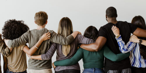 Grupo de personas mirando al mismo sitio abrazándose de espaldas