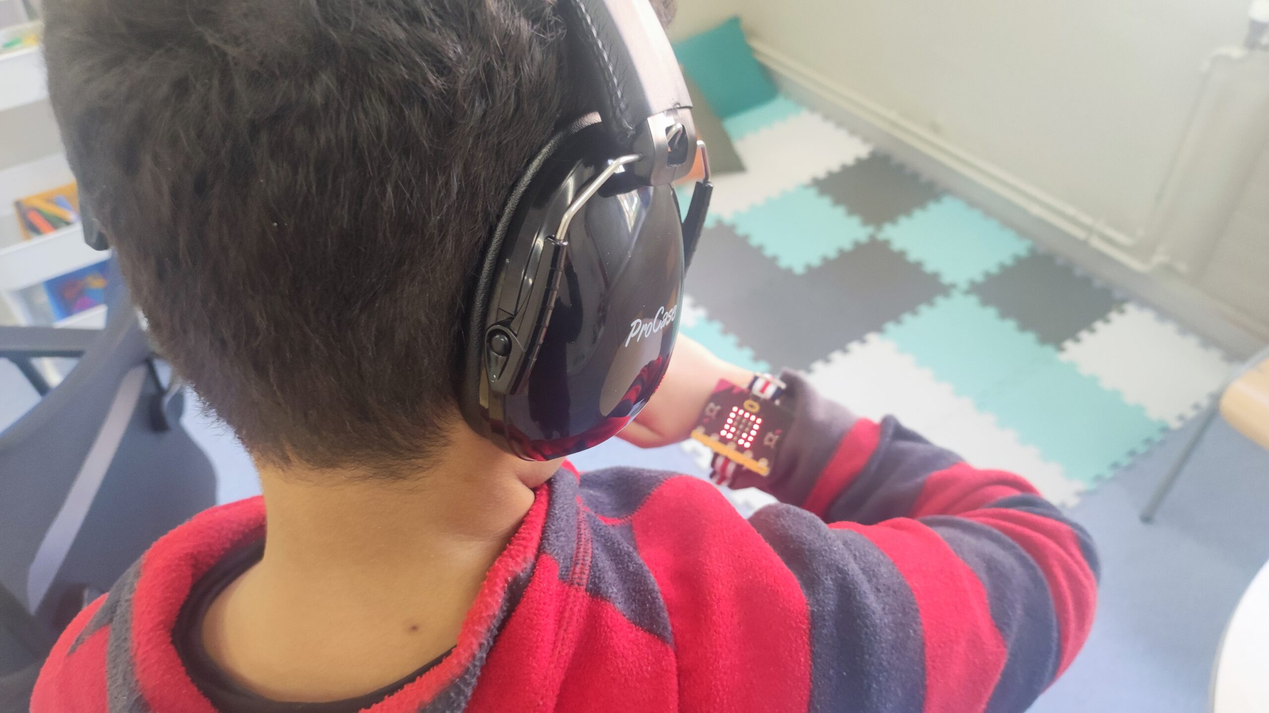 Alumno TEA testeando el sonómetro pulsera con los auriculares de cancelación de ruido Alumno TEA testeando el sonómetro pulsera con los auriculares de cancelación de ruido