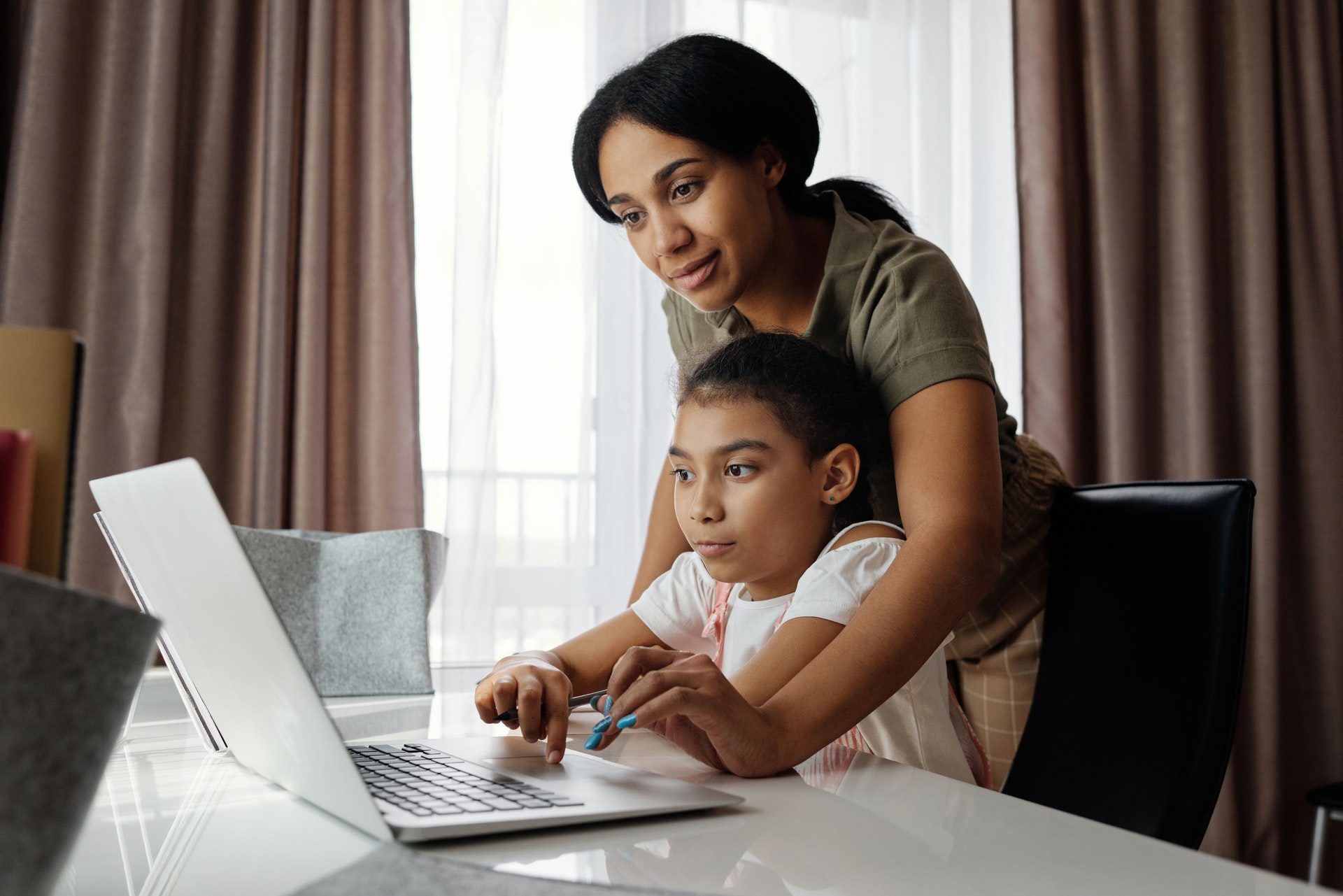 Niña y madre trabajando en un portátil