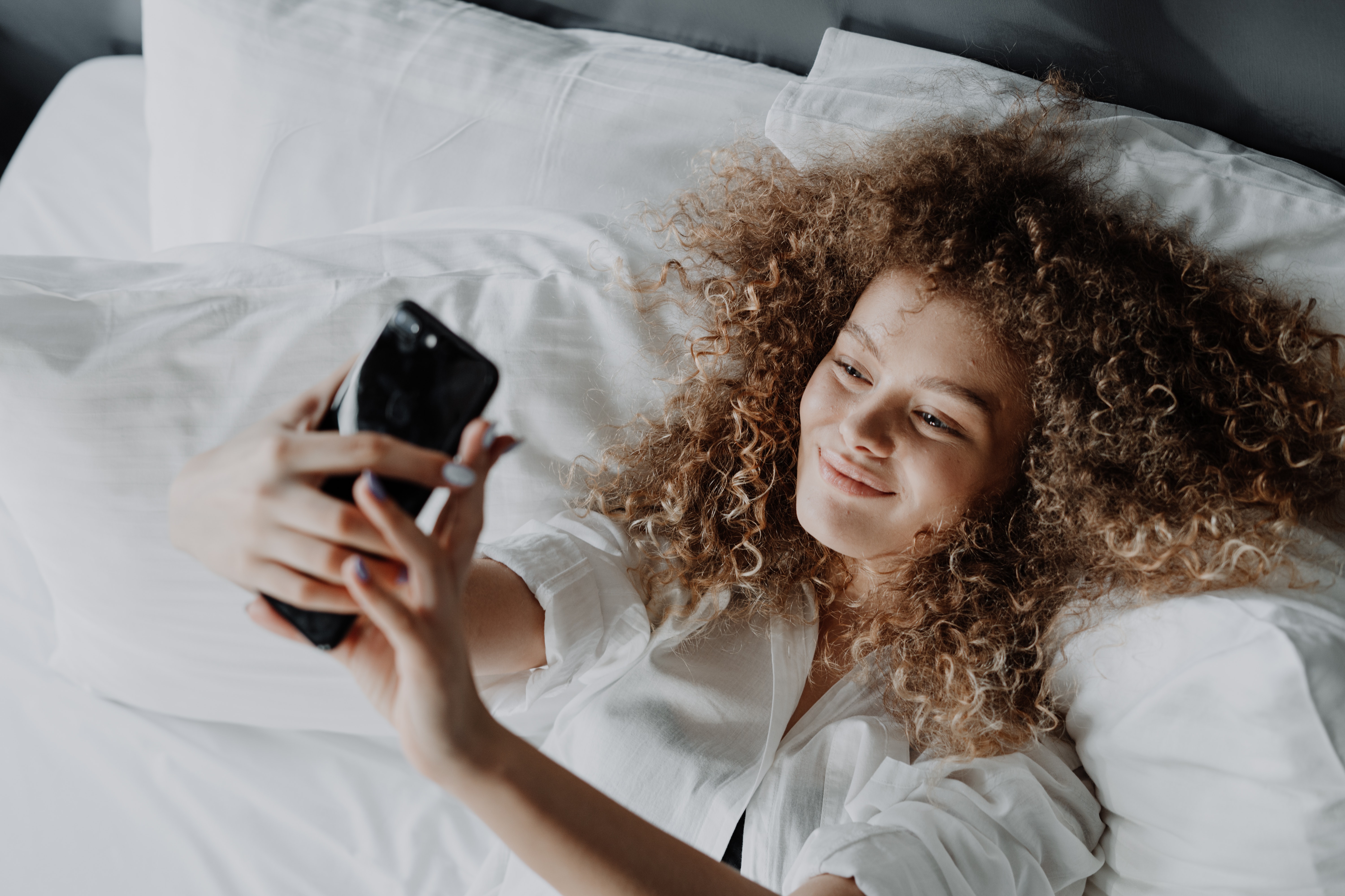 Chica haciéndose un selfie en la cama