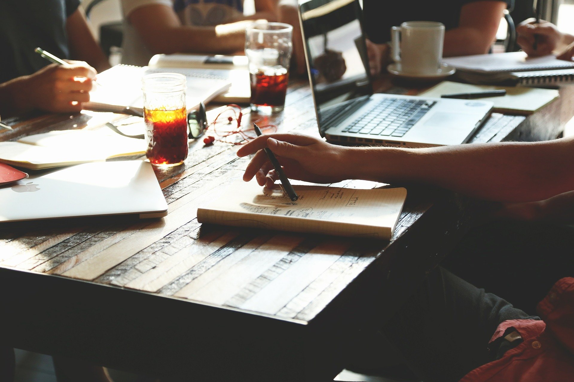 personas reunidas, sentadas a una mesa, con cuadernos y ordenadores para trabajar.